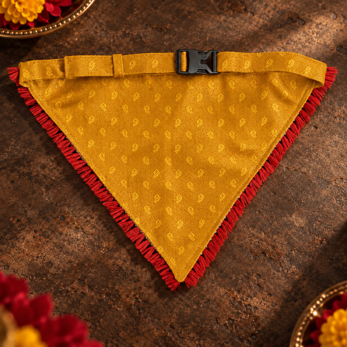 Reverse view of the mustard-yellow and red ethnic dog bandana, showing its jacquard fabric, red fringe, adjustable strap and buckle.
